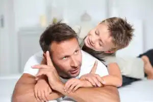 אב ובנו משחקים, הבן שוכב על גב האב, בהקשר הורות ופונדקאות
