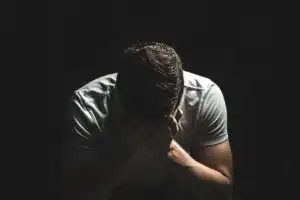 גבר עצוב אוחז בראשו על רקע כהה, בהקשר אלימות במשפחה ומצוקה