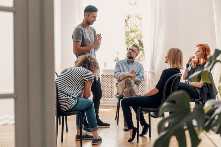 Happy hispanic man talking to his support group about his success