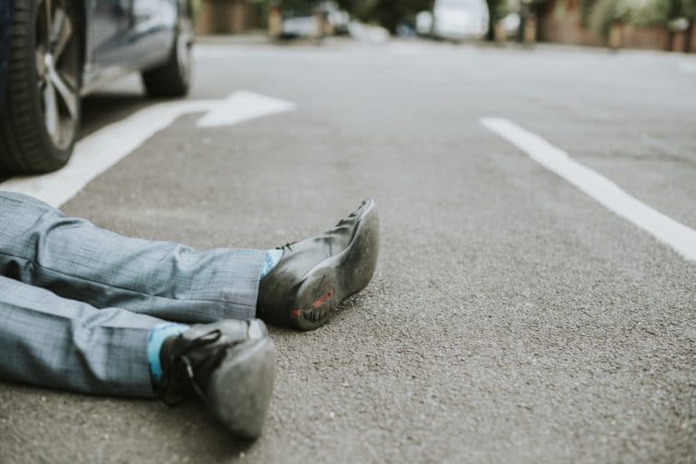 Person lying on the ground after a car accident