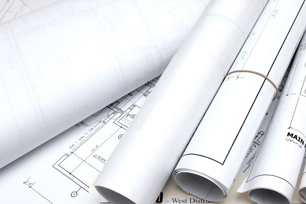 ערימה של שרטוטים אדריכליים על שולחן.