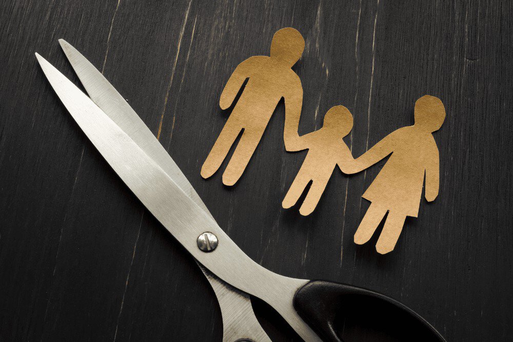A pair of scissors next to a paper cut out of a family.