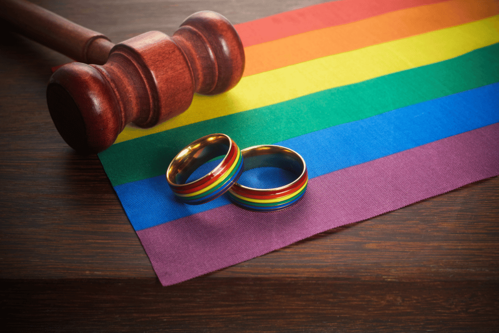 Two wedding rings and a gavel on a rainbow flag.