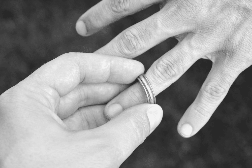 A man is putting a wedding ring on a woman's hand.