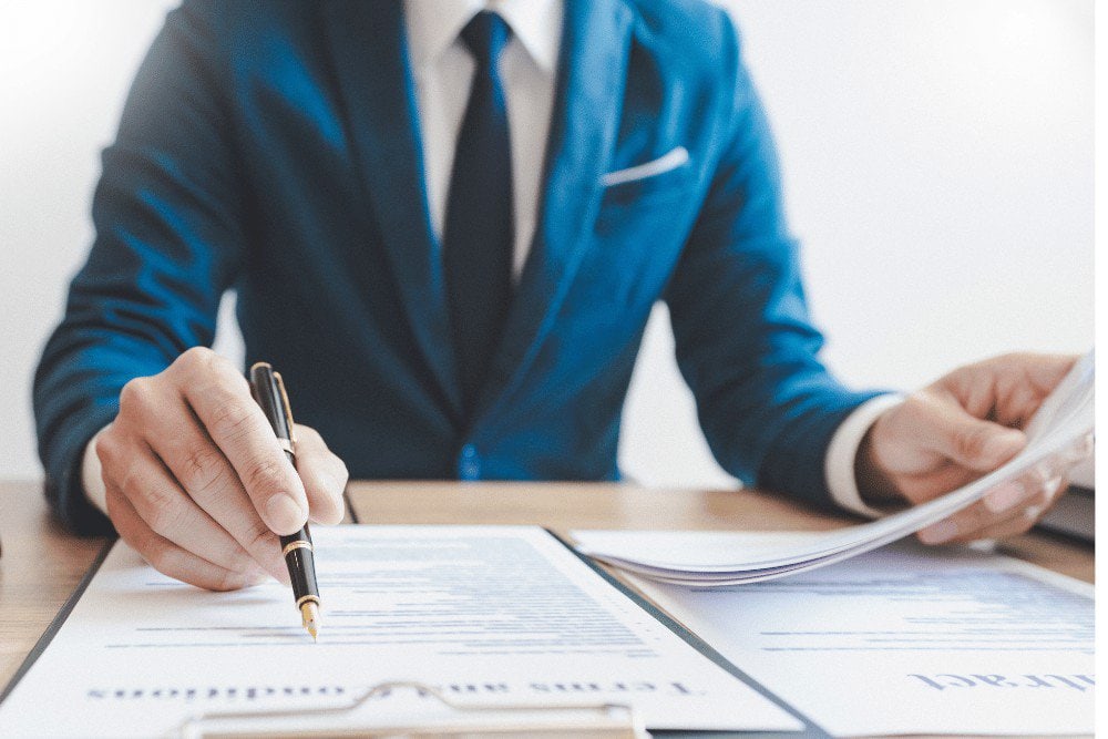 A businessman signing a document at a desk.