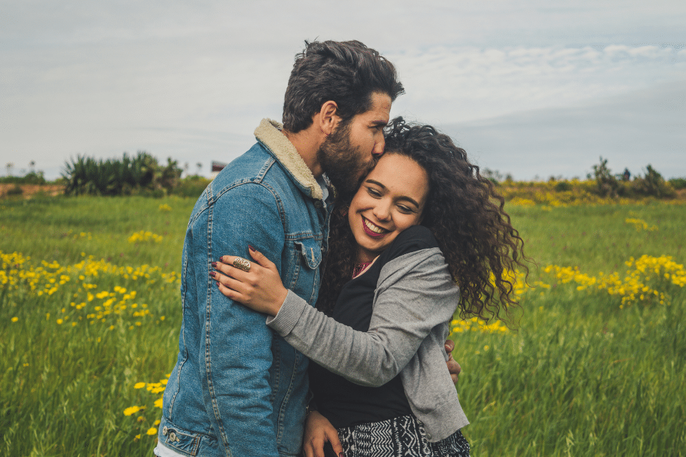 A couple embracing in a field of yellow flowers.