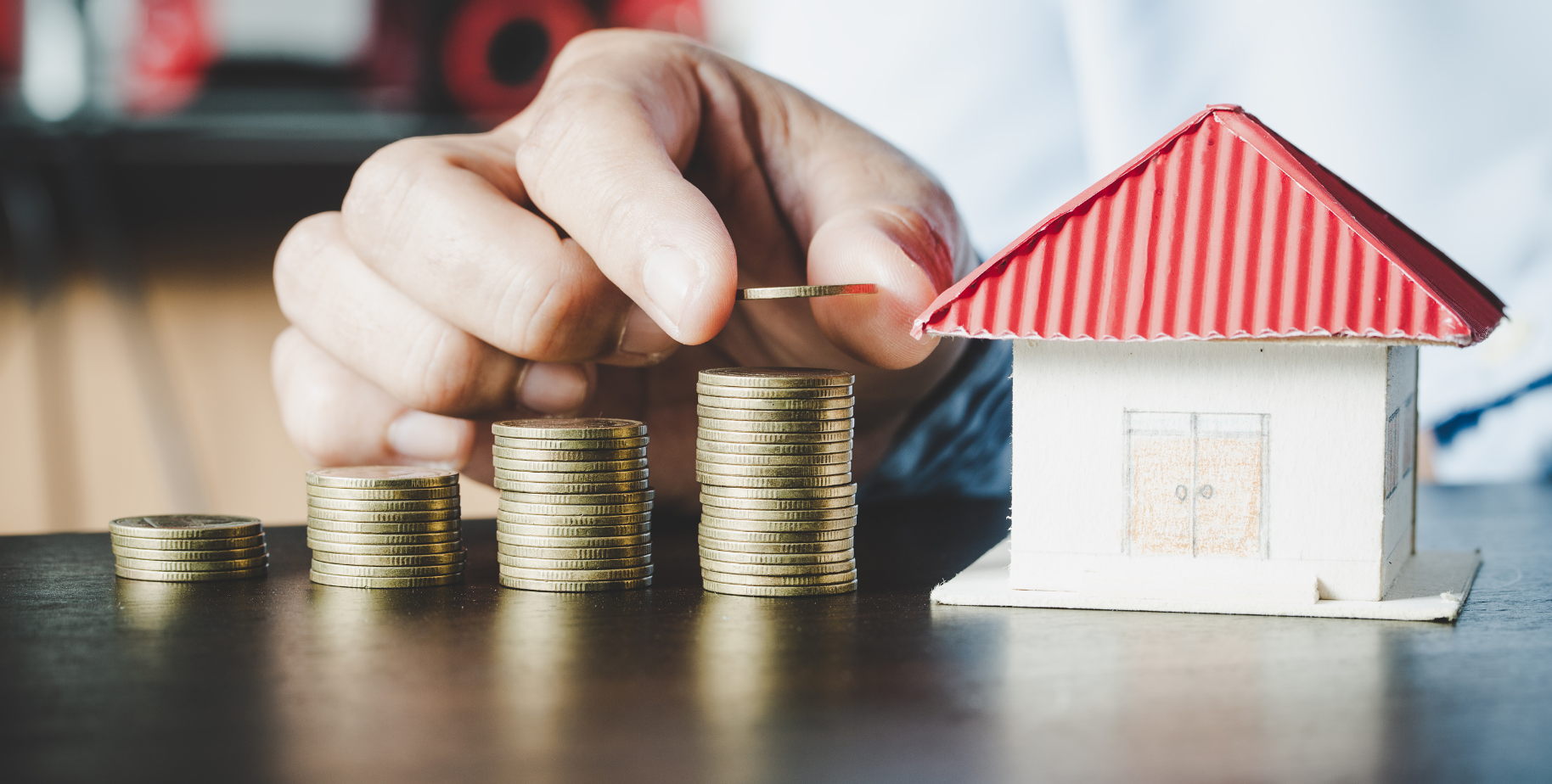 Stacks of coins beside a model house