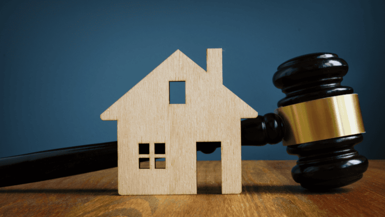 דגם בית עץ עם פטישת שופט על רקע כחול, המסמל סוגיות משפטיות הקשורות בדיני מקרקעין או מקרקעין.